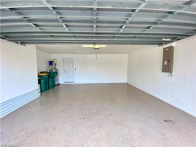 Enclosed two-car garage featuring a textured concrete floor, neutral wall finishes, and an integrated electrical panel
