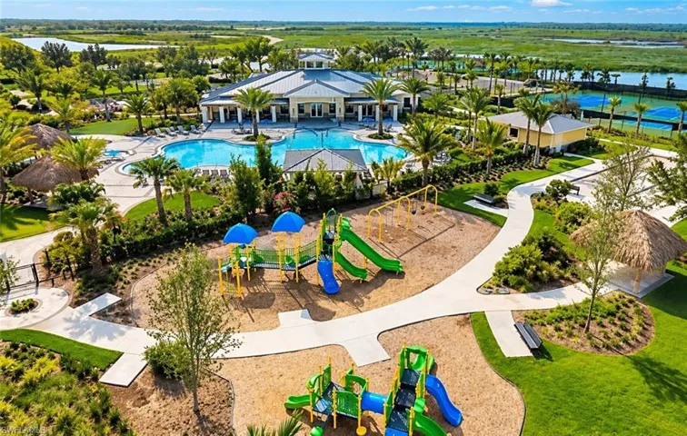 Community recreation area featuring a swimming pool, multiple playgrounds with play structures, tennis courts, and walking paths surrounded by landscaped grounds