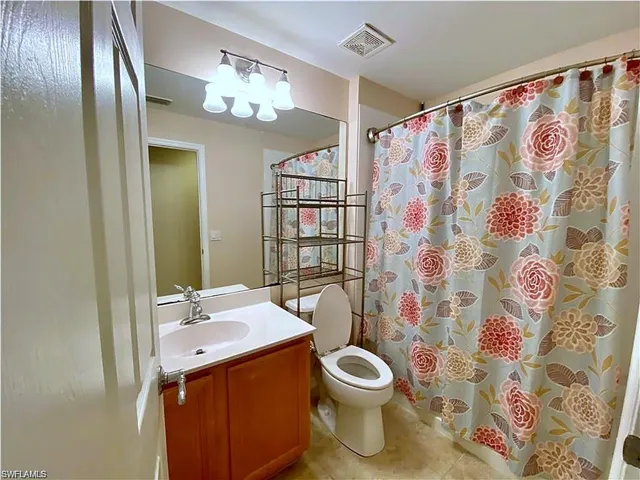 Bathroom featuring a vanity with a white countertop and integrated sink, full-width mirror, five-light fixture, and shower-tub combination with a curtain rod