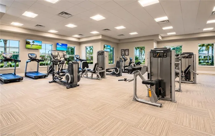 Fitness center featuring expansive floor space, commercial-grade exercise equipment, modular carpet tiling, recessed ceiling lighting, and abundant windows