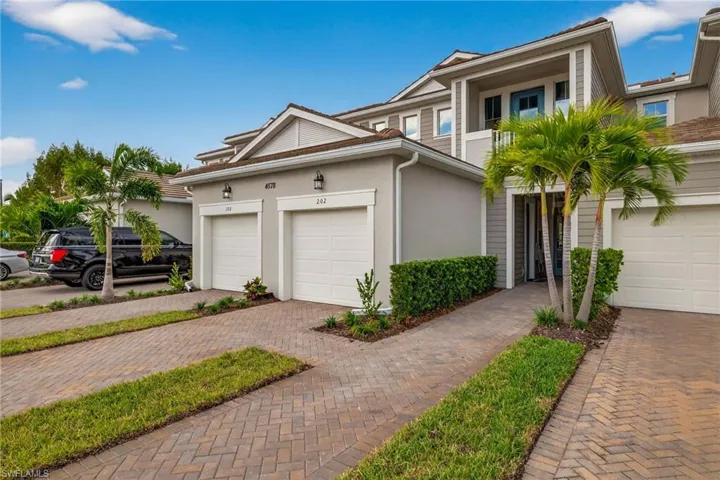View of front of house with stucco siding, a balcony, a garage, and decorative driveway