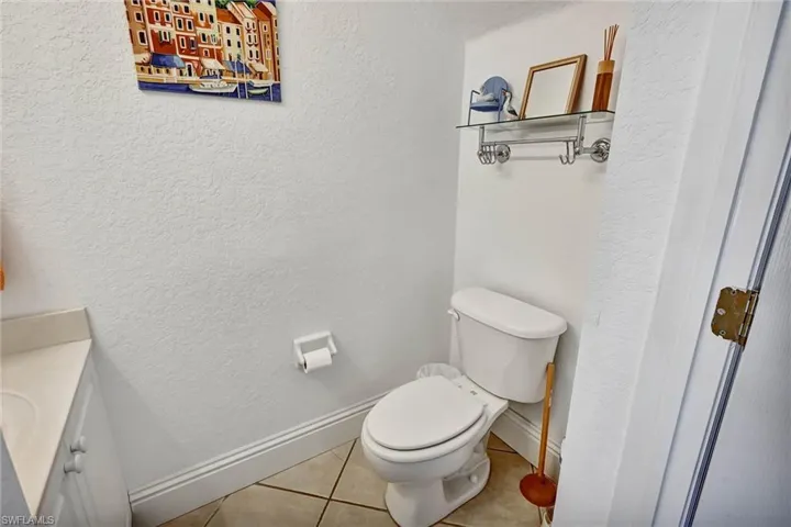 Compact bathroom featuring a white toilet, tile flooring, and a vanity with a countertop and under-sink cabinetry