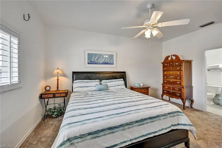 Carpeted room featuring a ceiling fan with integrated lighting, white walls, and a window with plantation shutters