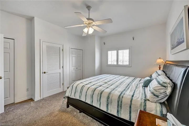 Bedroom featuring neutral carpeting, white walls, and a ceiling fan