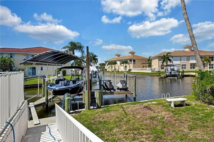 Waterfront property featuring a covered boat lift, additional dockage, canal access, and a sloped concrete path to the water