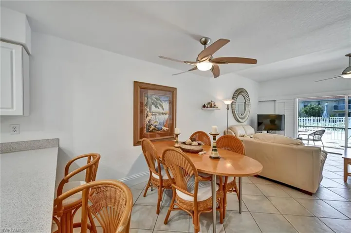 Open-concept living area featuring a dining space with a ceiling fan, tile flooring throughout, and white walls