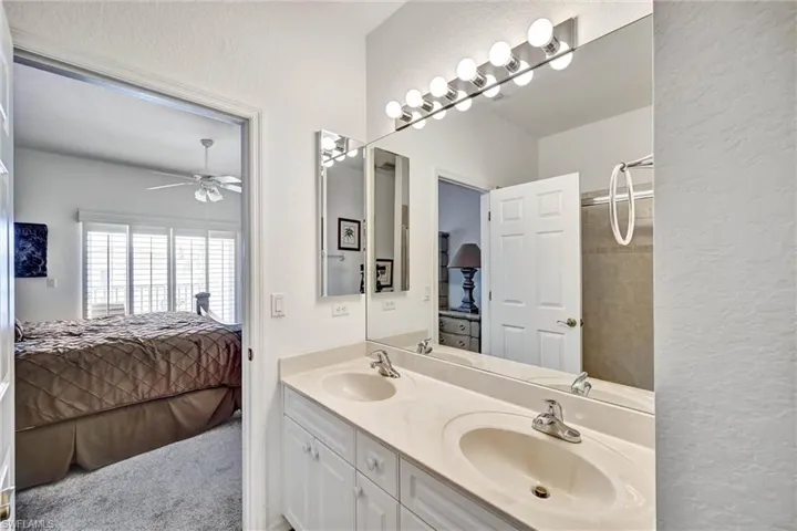 Dual vanity with integrated sinks, white cabinetry, and large wall-mounted mirror