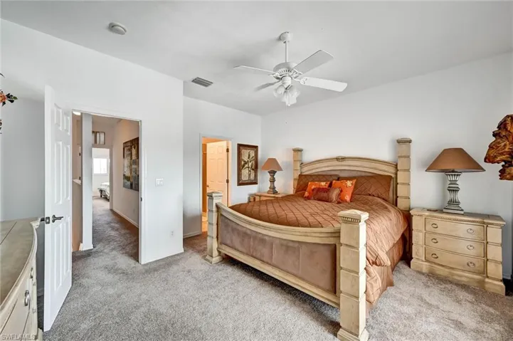Carpeted room with a ceiling fan, white walls, and a multi-panel interior door