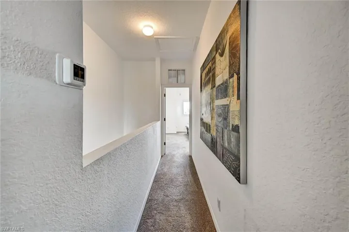 Upper-level hallway featuring textured walls and carpet flooring