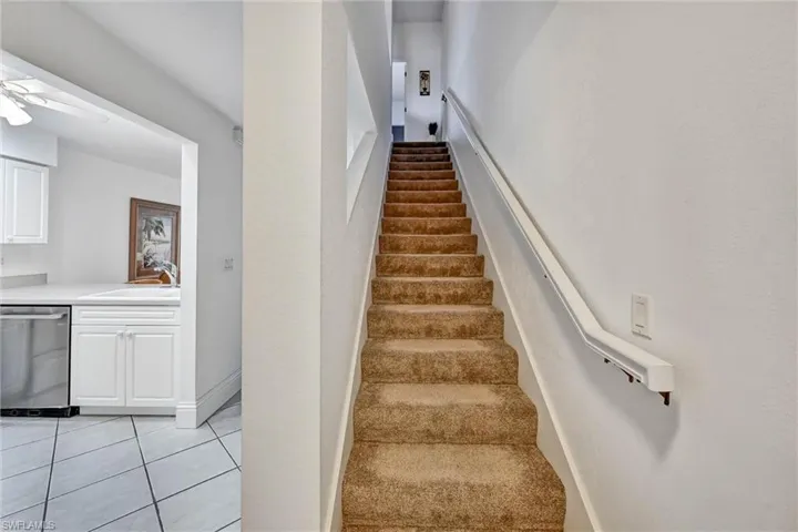 Carpeted staircase with white handrail and textured walls