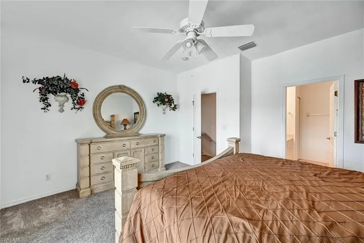 Carpeted interior space with a ceiling fan and white walls