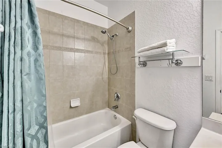 Bathroom featuring a white tub, chrome fixtures, and tiled shower surround with decorative accent band