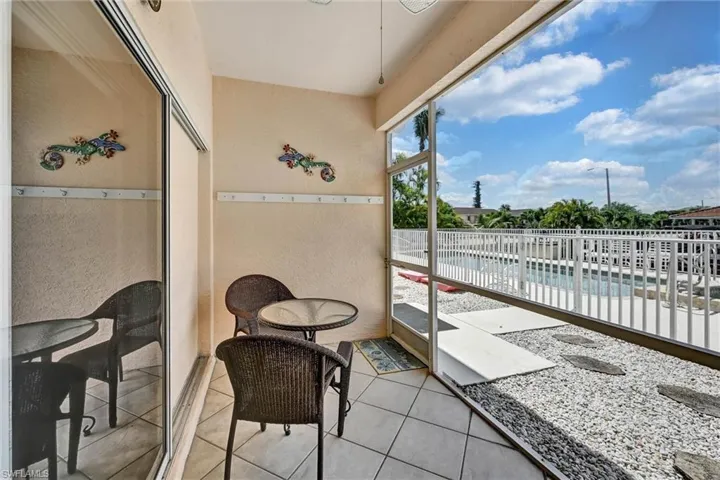 Tiled patio space with sliding glass doors, textured wall finishes, and an exterior screened enclosure