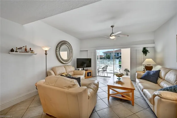 Living area featuring tile flooring, a ceiling fan with integrated lighting, and sliding glass doors opening to an outdoor patio space