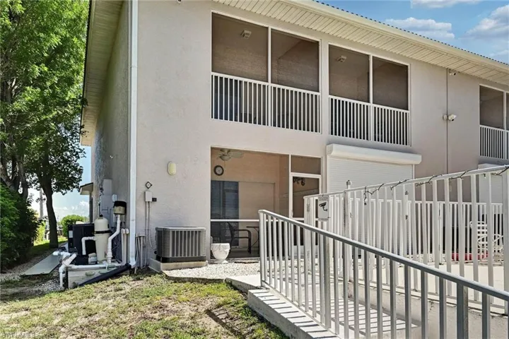 Rear exterior featuring a screened balcony, ground-level screened patio, and an accessible ramp entry