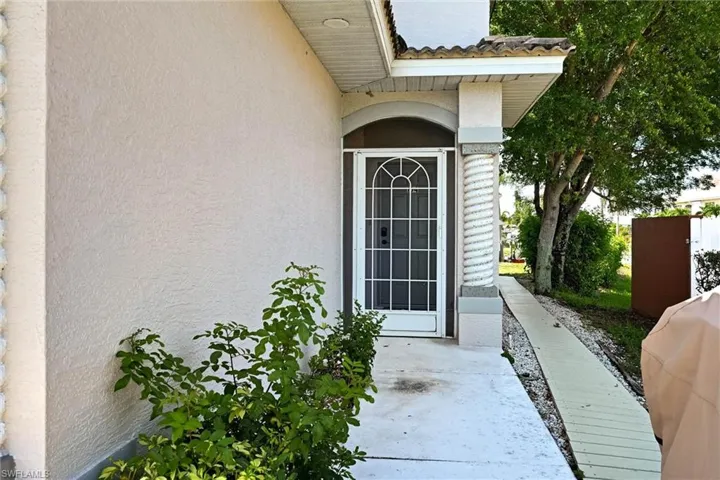 Front entrance featuring a security screen door, an arched transom, a decorative spiral column, and stucco exterior