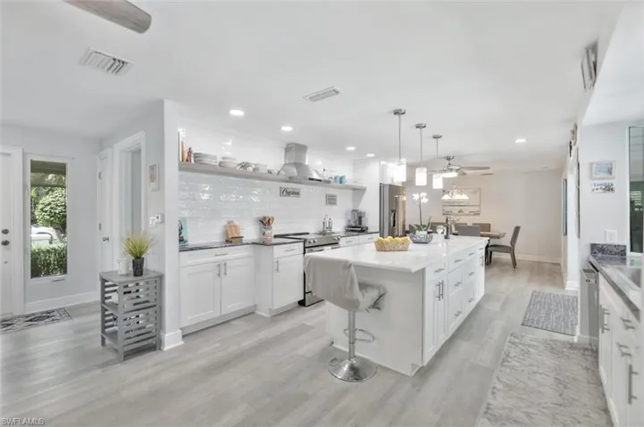 Kitchen with white cabinets, decorative backsplash, stainless steel appliances, pendant lighting, and recessed lighting