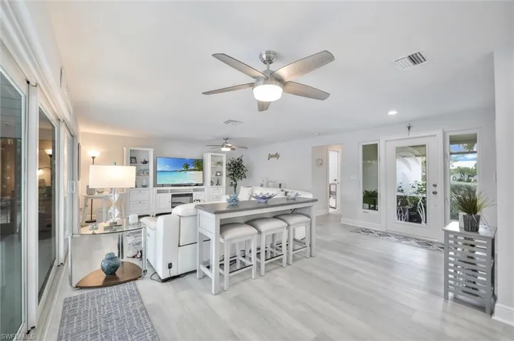 Living area featuring light wood-style floors, ceiling fan, and recessed lighting