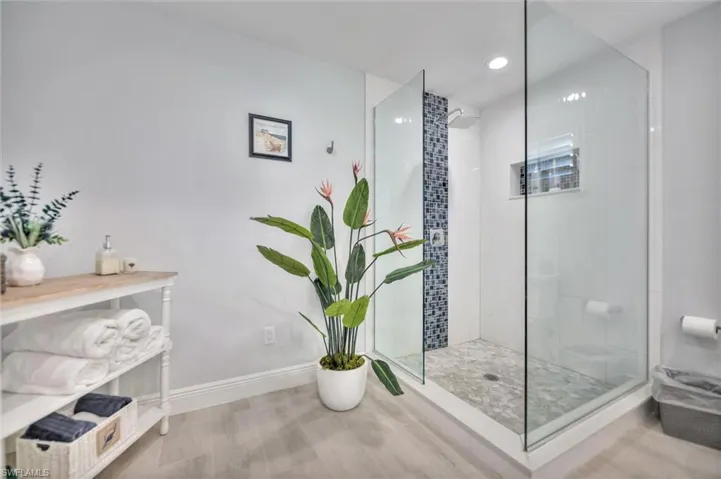 Bathroom featuring a walk in shower, wood finished floors, and recessed lighting
