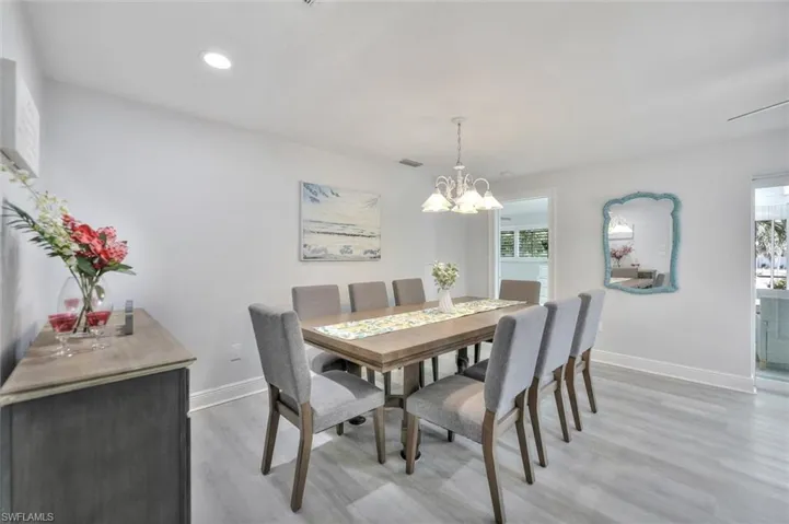 Dining room with light wood finished floors, a chandelier, and recessed lighting