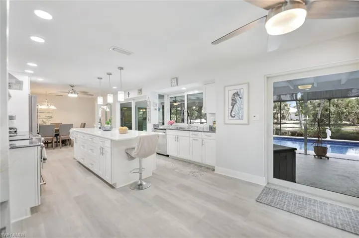 Kitchen featuring ceiling fan, white cabinets, hanging light fixtures, a kitchen island, and recessed lighting