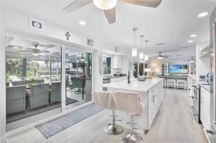 Kitchen with a kitchen breakfast bar, white cabinetry, light wood-style floors, a ceiling fan, and recessed lighting
