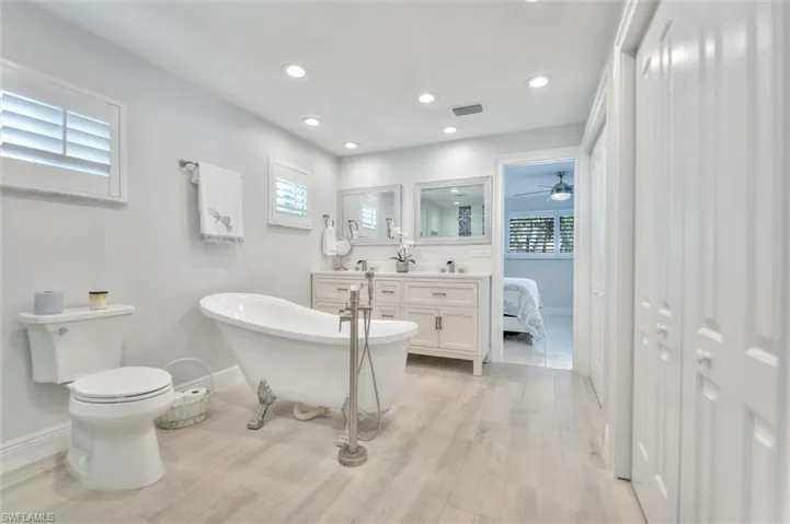 Full bathroom with a freestanding bath, double vanity, recessed lighting, ensuite bath, and light wood-style floors