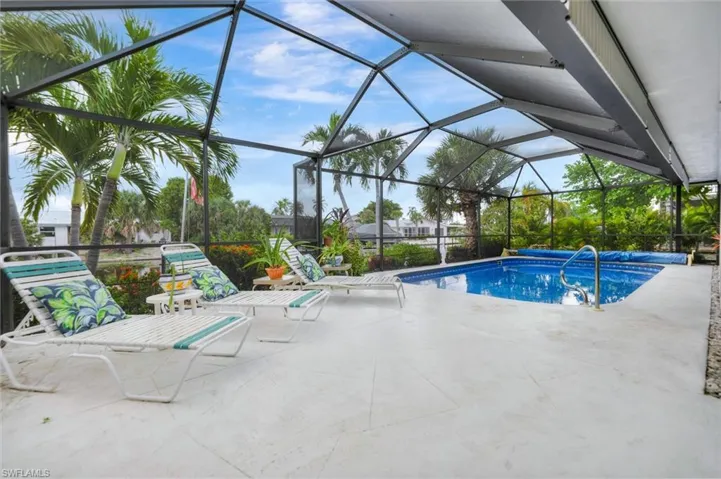 Swimming pool featuring a patio area, glass enclosure, and a sunroom