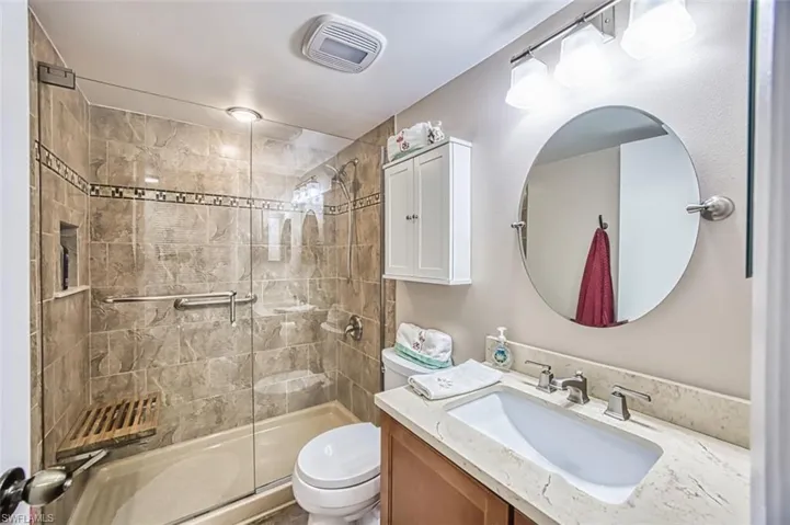 Bathroom with toilet, a stall shower, and vanity