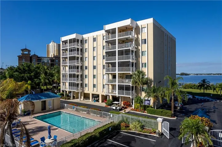 View of apartment building / complex featuring uncovered parking, a community pool, and a water view
