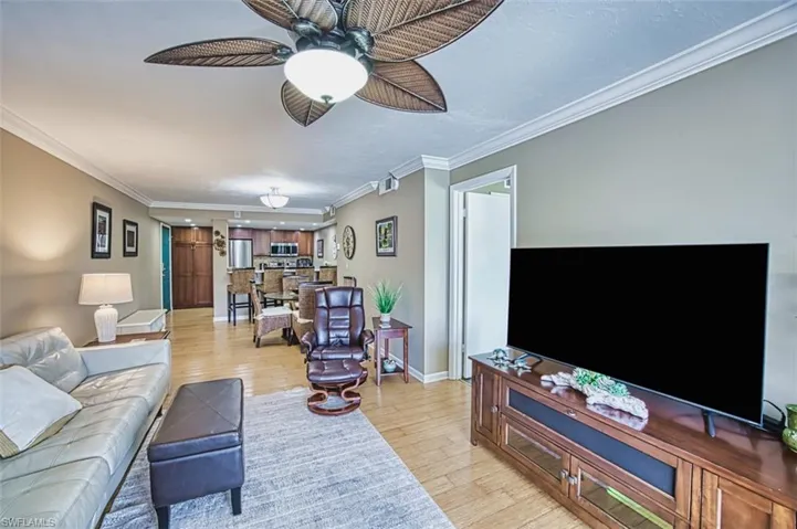 Living room featuring crown molding, a ceiling fan, baseboards, and light wood-type flooring