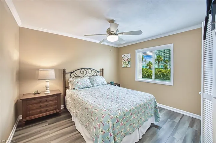 Bedroom featuring crown molding, baseboards, wood finished floors, and ceiling fan