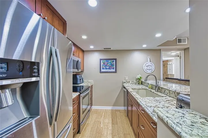 Kitchen featuring stainless steel appliances, a sink, light wood-style flooring, recessed lighting, and brown cabinets
