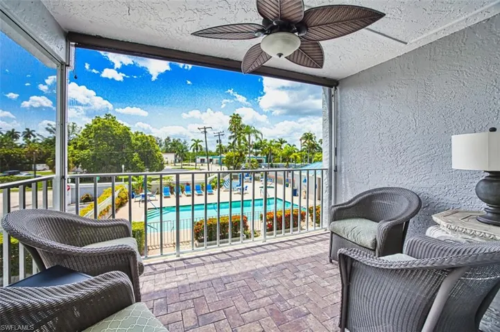 View of patio with a ceiling fan, a balcony, and an outdoor pool