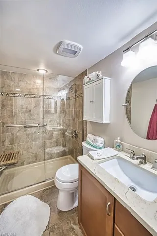 Full bathroom with a shower stall, vanity, toilet, and a textured ceiling