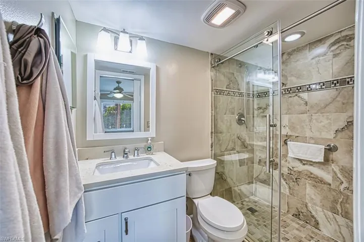 Full bathroom featuring toilet, vanity, and a stall shower