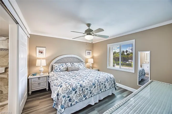 Bedroom featuring dark wood-style flooring, crown molding, baseboards, a closet, and ceiling fan