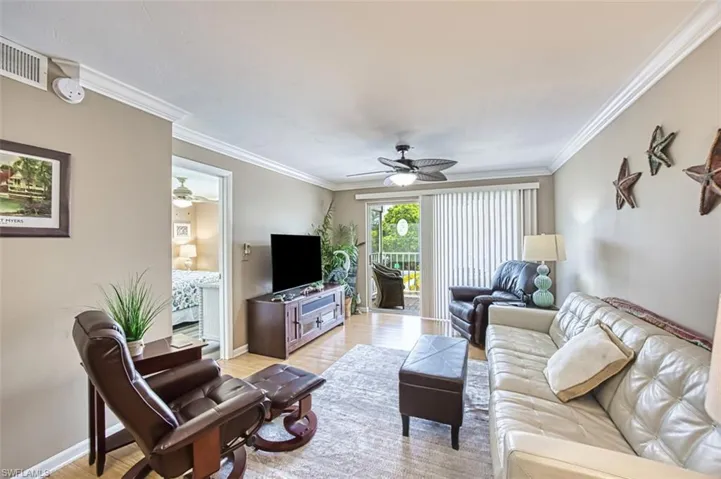 Living area with ceiling fan, crown molding, light wood finished floors, and baseboards