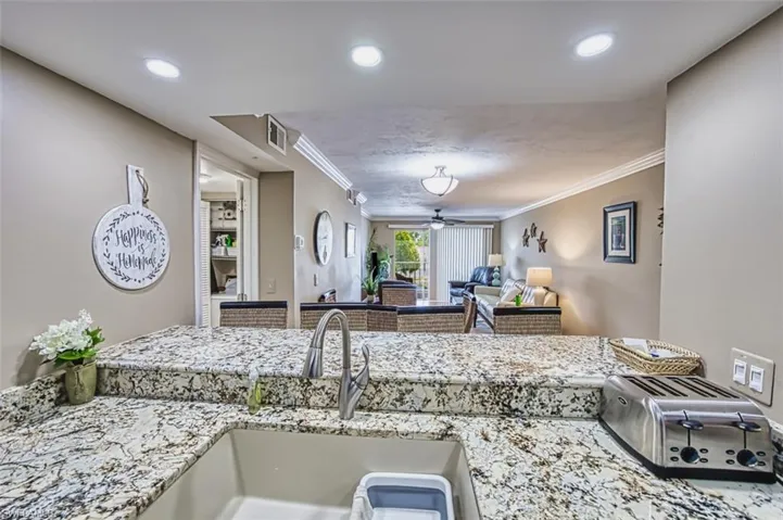 Kitchen with a sink, crown molding, ceiling fan, light stone countertops, and recessed lighting