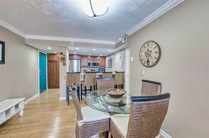Dining room with ornamental molding, light wood-type flooring, baseboards, and recessed lighting