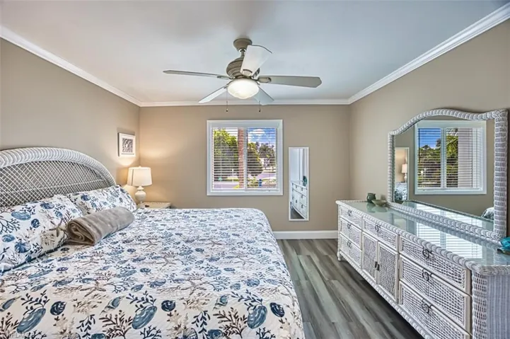 Bedroom featuring crown molding, dark wood-style floors, baseboards, and a ceiling fan