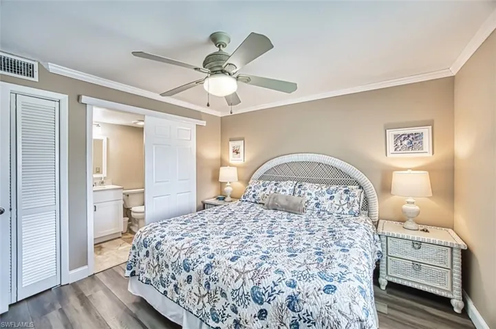 Bedroom with wood finished floors, crown molding, baseboards, ceiling fan, and connected bathroom