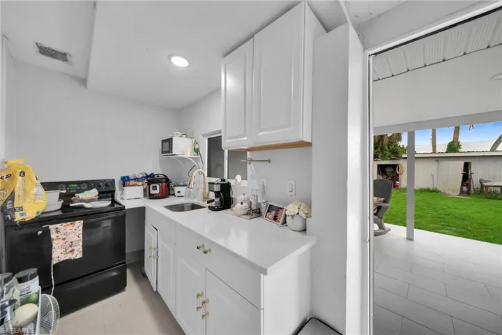 Kitchen featuring black appliances, white cabinets, and sink