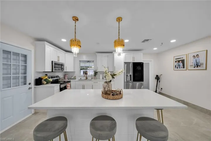 Kitchen featuring white cabinetry, decorative light fixtures, stainless steel appliances, and a notable chandelier
