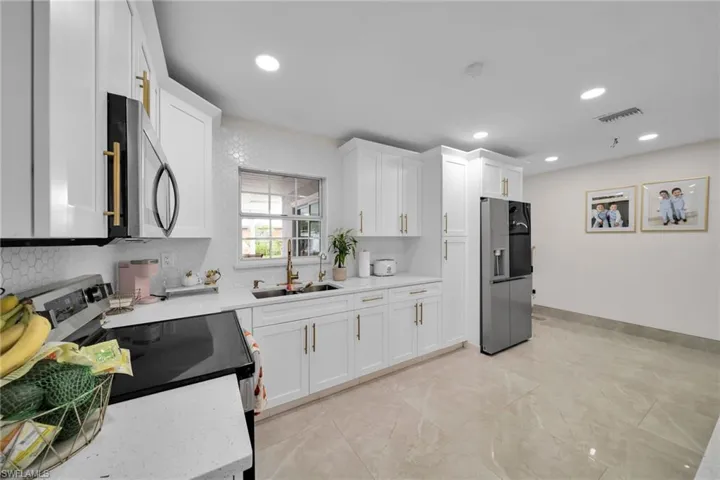 Kitchen featuring sink, appliances with stainless steel finishes, white cabinets, and decorative backsplash
