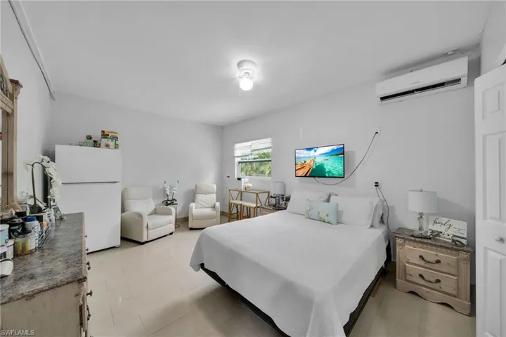 Bedroom featuring white fridge and a wall unit AC