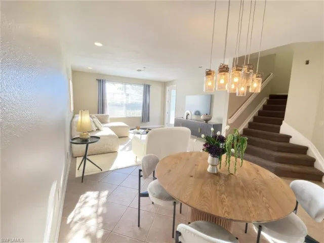Tiled dining area with a chandelier, stairs, and recessed lighting