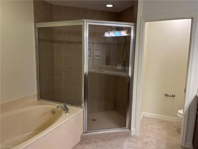 Bathroom with a stall shower, light tile patterned flooring, and a garden tub