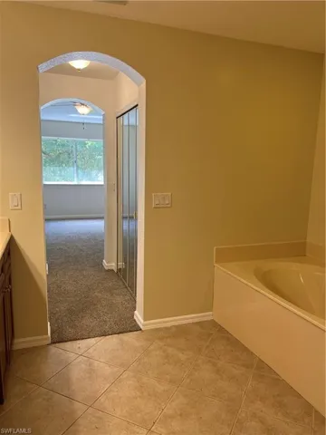 Full bath with a garden tub, vanity, and light tile patterned flooring