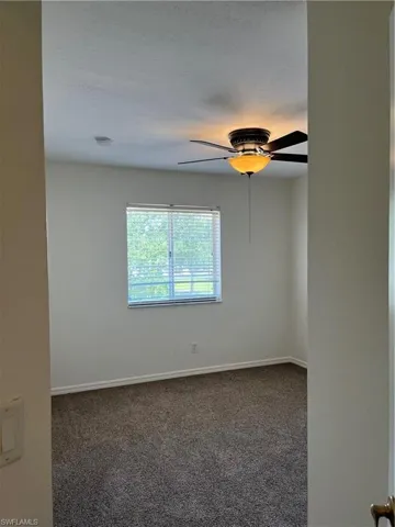 Empty room with dark carpet and ceiling fan